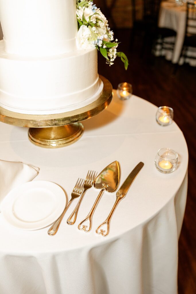 A white wedding cake on a gold cake stand featuring one of our Fishermen's Inn Rentals: our gold cake serving set.