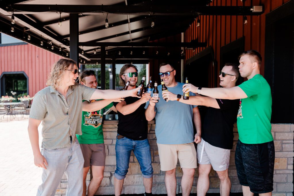 Groom and groomsmen enjoying pre-wedding time playing bags and having a beer on the patio | Friday Weddings at Fishermen's Inn