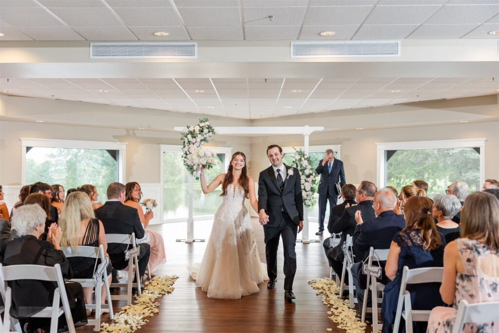 The bride and groom celebrate saying "I Do" as they walk down the aisle in the Veranda.