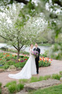 A bride and groom stand in the courtyard at Fishermen's Inn surrounded by lush gardens and tulips during a Spring wedding.