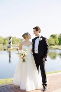 Bride and groom standing by the ponds at Fishermen's Inn during a spring wedding with the lighthouse in the background.