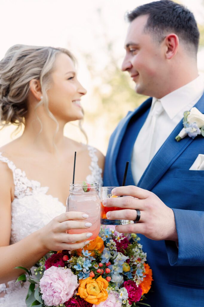 bride and groom holding drinks with spring floral bouquet
