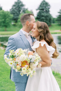 Bride and groom embracing by the pond during their June wedding at Fishermen's Inn in Elburn, Illinois.