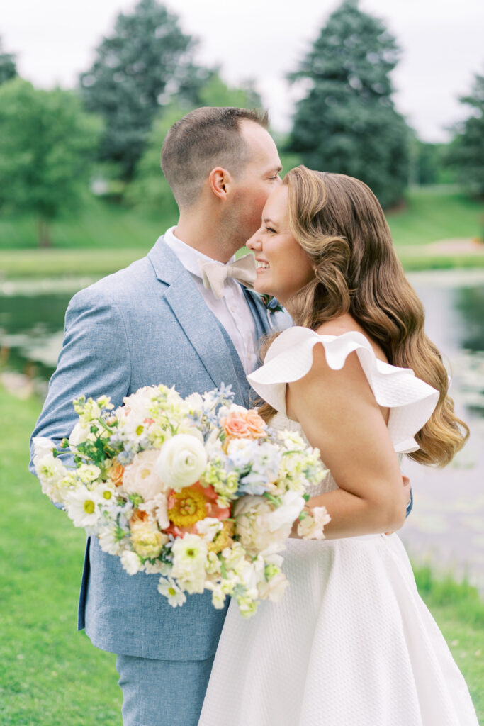 Bride and groom embracing by the pond during their June wedding at Fishermen's Inn in Elburn, Illinois.