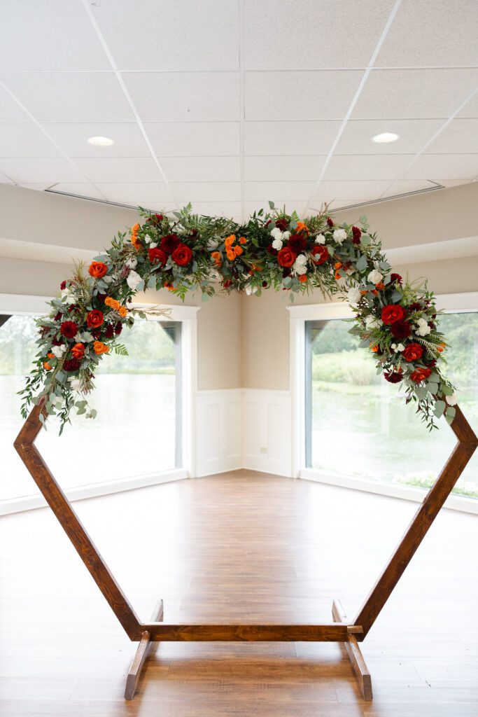 Colorful floral arch arranged for an indoor fall wedding ceremony at Fishermen’s Inn.