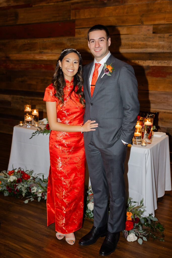 Tina wears her red Chinese dress while standing with Connor during their reception.