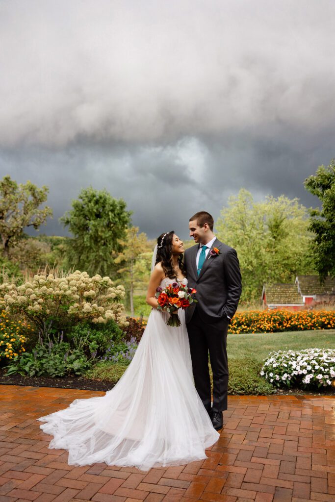 Tina and Connor stand together in the gardens beneath dark September storm clouds.