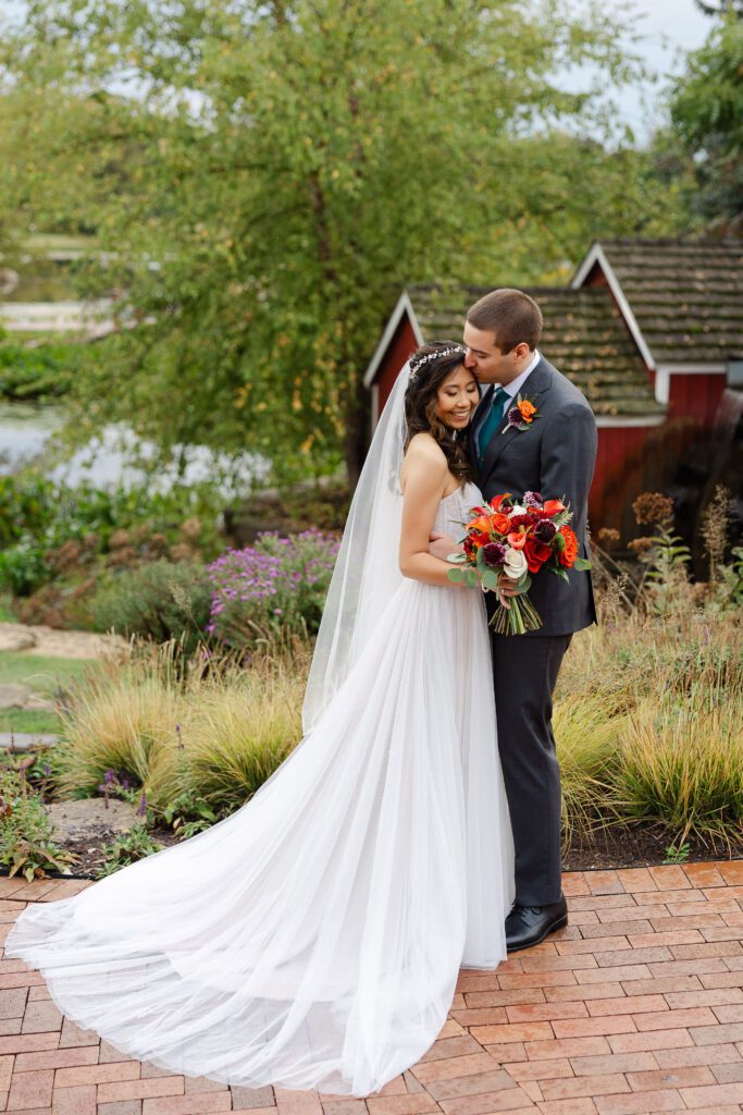 Tina and Connor kiss along a brick garden path at Fishermen’s Inn.