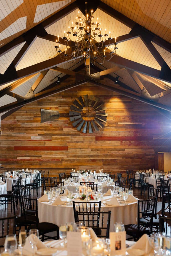 Warmly lit barn reception room prepared for Tina and Connor’s wedding celebration.
